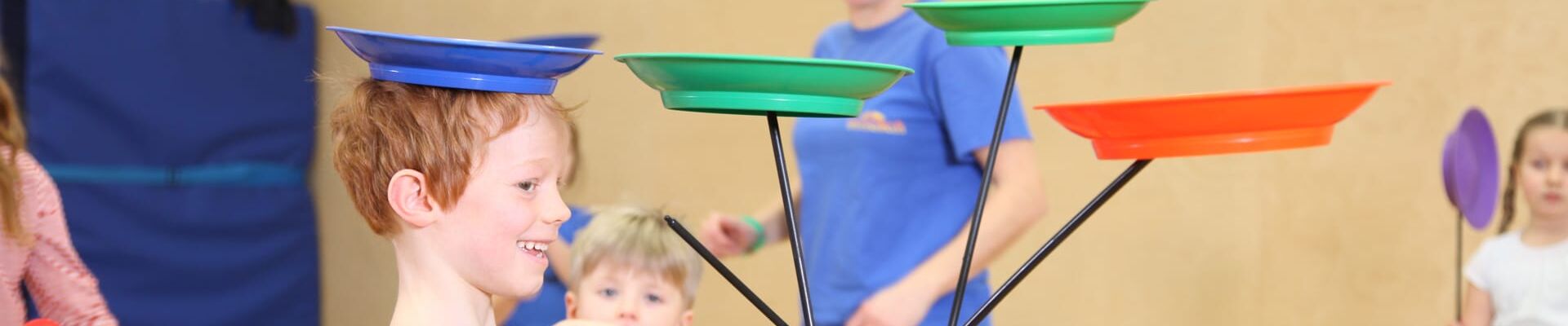 Kind aus Kita jongliert mit drei Tellern im Kölner Spielecircus