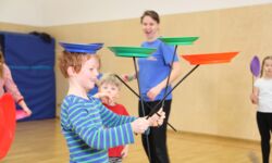 Ein Zirkuskind jongliert 4 Jonglierteller gleichzeitig in der Zirkusschule
